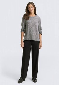 Gray patterned long-sleeve top with a crew neckline, paired with black wide-leg trousers and black shoes. Features rolled sleeves.
