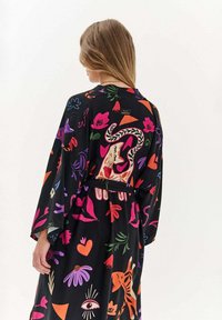 Černý kimono stylový župan s živým, multikolorovým květinovým a abstraktním vzorem. Obsahuje zavázaný pas a široké rukávy.
