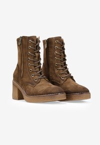 Stivali ankle in suede marrone con superficie strutturata, allacciatura frontale, cerniere laterali e tacco a blocco, con dettagli hardware in tono oro.