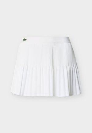 Jupe plissée blanche avec une large ceinture et un petit logo de crocodile vert près du coin supérieur gauche.