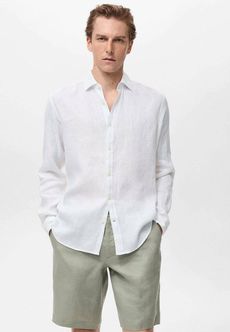Camisa de lino blanca de manga larga con cuello abotonado y pantalones cortos de lino verde claro, que presentan un ajuste relajado y una textura suave.