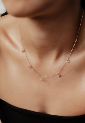 Zarte Goldkette mit fünf kleinen Kristallakzenten, gleichmäßig verbunden. Das Design ist minimalistisch mit einer glatten Textur.