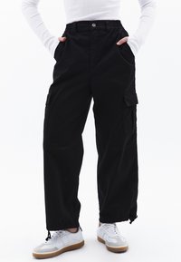 MIT ENGEN BEINABSCHLÜSSEN - Pantalon cargo - black