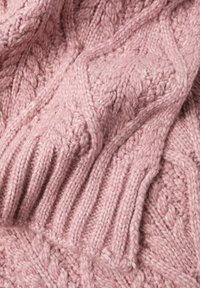 Rózsaszín kötött anyag mintázott kábelmintával és bordázott szegélyekkel. A textília vastagnak és kényelmesnek tűnik, részletes hímzésmintákat mutatva.