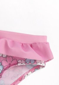 Rosa blommig bikiniunderdel med ett volangmidje, som har en slät yta och intrikata sömmar längs kanterna.