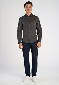 Donkergrijze shirt met knopen en lange mouwen, slim fit, gecombineerd met marineblauwe broek en witte sneakers. Eenvoudig, modern ontwerp, gladde textuur.