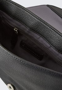 Borsa a tracolla nera in pelle con una texture a ciottoli, dotata di una tasca con zip all'interno e fodera in tessuto scuro e liscio. Chiusura con bottone a pressione argento.