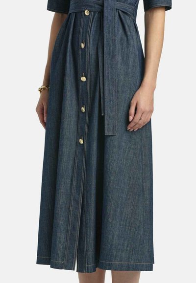 Farmer ruházat, kötött derékkal, rövid ujjakkal és teljes szoknyával. Aranyszínű gombokkal és kontrasztos varrással rendelkezik, sötétkék árnyalatban.