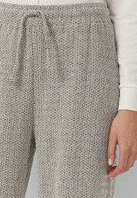 Texturierte, beigefarbene Lounge-Hosen mit elastischem Bund und Kordelzug. Verfügt über ein gestricktes Muster und eine lockere Passform. Weicher Stoff sichtbar.