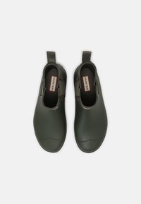 Bottes de cheville vertes imperméables en caoutchouc, dotées d'une texture lisse, de panneaux latéraux élastiques et de petites languettes de tirage pour un enfilage facile.