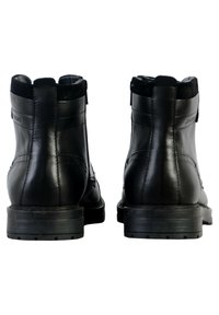 Botas negras de cuero hasta el tobillo con un acabado mate, panel trasero texturizado y suelas de goma planas. Presentan costuras mínimas y un diseño simple.