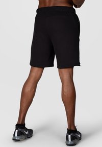 Pantaloni sportivi neri realizzati in tessuto morbido, con vita elasticizzata e tasche laterali. I pantaloni hanno una vestibilità ampia e un orlo semplice.