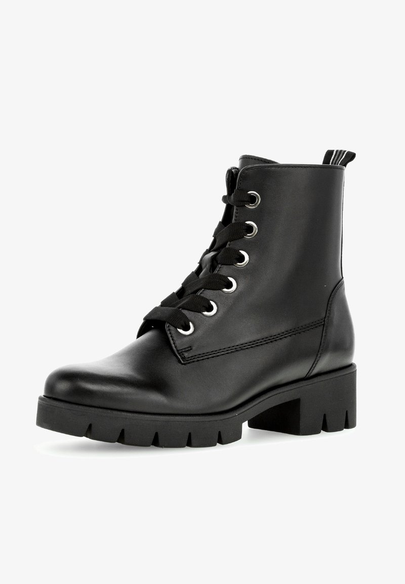 Bottine noire en cuir avec semelle épaisse à crampons, talon épais et bas, bout rond, lacets noirs et languette en tissu à l'arrière.