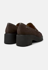 Brown suede heeled shoes with a chunky black rubber sole. Rounded toe and minimal design, featuring a small label on the side.