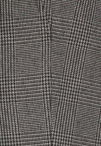 Tkanka w czarno-białą kratkę houndstooth, z drobnymi liniami w kratkę, tkanym wzorem i subtelnym połyskiem.