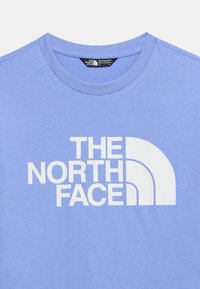 Ανοιχτό μωβ κοντομάνικο μπλουζάκι με στρογγυλή λαιμόκοψη και μεγάλο λευκό λογότυπο "The North Face" στο κέντρο του στήθους.