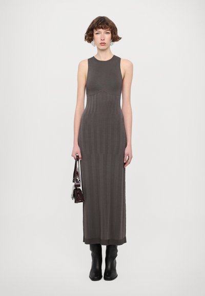 Long, form-fitting grey dress with a sleeveless design, ribbed texture, and a subtle pattern. Paired with black ankle boots and a small bag.