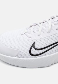 Weißer Sportschuh mit einem Obermaterial aus Mesh, strukturierten Akzenten, schwarzem Nike-Logo und einer Schnürung mit gepolstertem Rand.