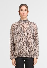 Lekka beżowa bluzka w tygrysie paski, z wysokim marszczonym kołnierzem, drapowanym krojem i elastycznym dołem. Długie rękawy z marszczonymi mankietami.