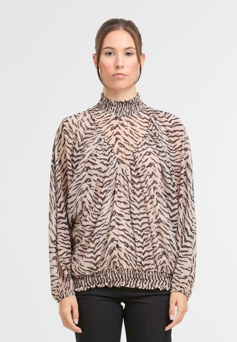 Lekka beżowa bluzka w tygrysie paski, z wysokim marszczonym kołnierzem, drapowanym krojem i elastycznym dołem. Długie rękawy z marszczonymi mankietami.