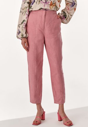 Rosa Leinenhosen mit taillierter Passform, gerade Beine und vorderen Nähten. Kombiniert mit rosa Sandalen mit Blockabsatz.