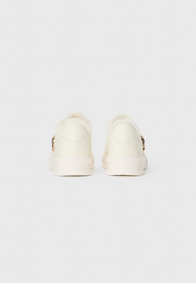 White sneakers featuring a soft, fluffy back, textured upper, and subtle gold hardware accents on the side. Rounded toe and thick sole.