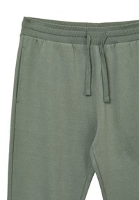 Hellgrüne Jogginghose mit Kordelzugbund, ausgestattet mit Seitentaschen und einer glatten Textur, entworfen für Komfort und lässigen Tragekomfort.