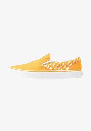 Scarpa slip-on in tela gialla con suola in gomma bianca. L'interno presenta un motivo ripetuto del logo Vans in bianco e arancione.