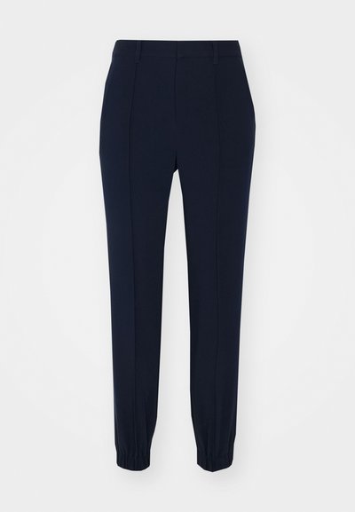 Marineblauwe tapering broeken met een gladde textuur, voorzien van elastische boorden, riemlussen en voorplooidetails. Gemaakt van een rekbare stof.