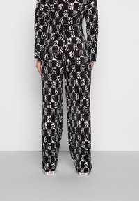 Czarno-białe spodnie we wzory o luźnym kroju i plisowanej fakturze, z różnorodnymi abstrakcyjnymi wzorami i wygodnym pasem.