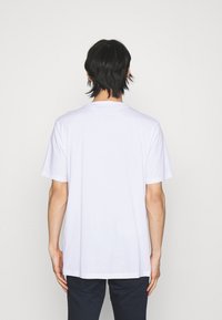 Hvid bomulds t-shirt med korte ærmer, rund hals og en afslappet pasform. Bagsiden har et ensartet design uden grafik eller accenter.