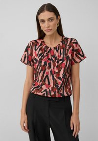 Kurzarmpullover aus einem seidigen Stoff, mit einem pink-rot abstrakten Muster und schwarzen Akzenten, sowie einem gerafften Halsausschnitt.