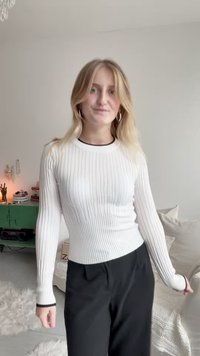 Valge soonilise pikakaelusega topp musta äärega, kombineeritud mustade pükstega. Sile tekstuur ja mugav lõige, toomine esile silueti.