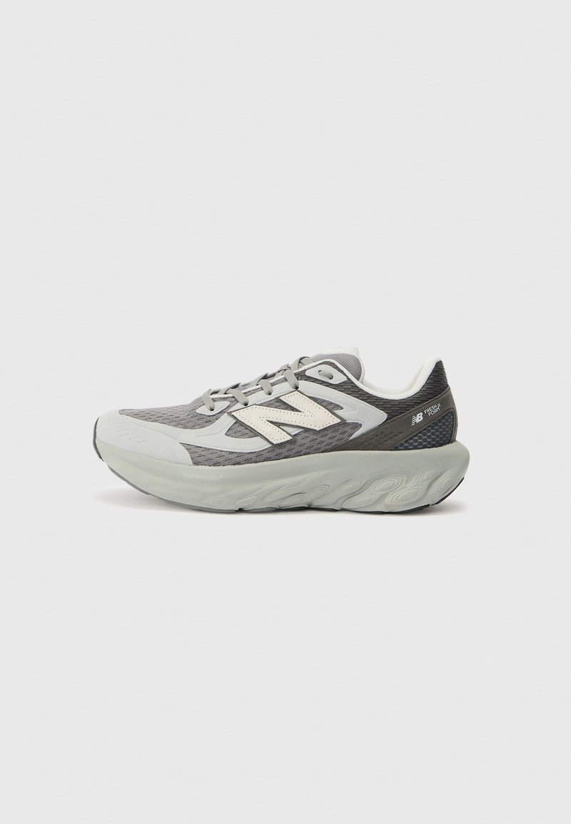 Chaussure de course New Balance grise et blanche avec semelle épaisse et rembourrée et tige en mesh, vue de profil sur fond uni clair.