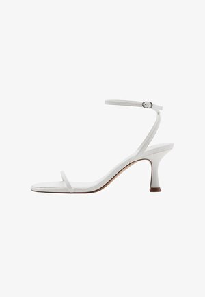 White high-heel sandals with a minimalist design, featuring a thin ankle strap, open toe, and a slender heel. Smooth texture and curved shape.