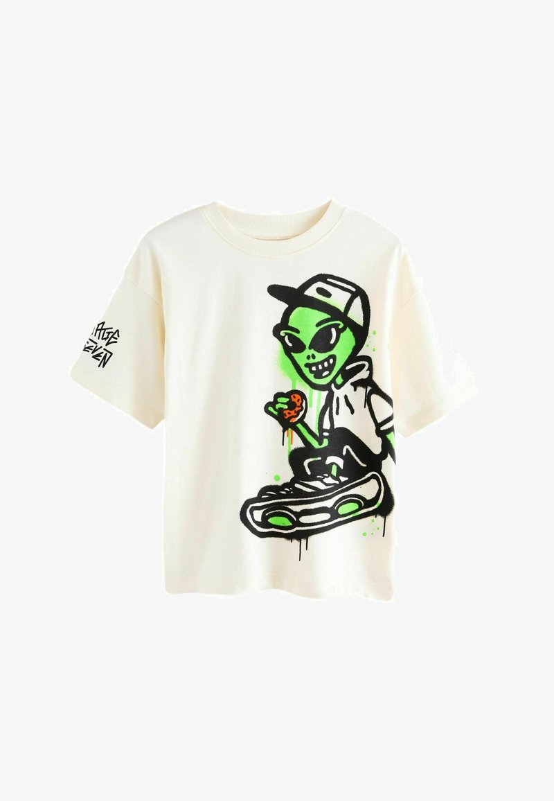 Cremefarbenes Kurzarm-T-Shirt mit einem lebendigen grünen Alien-Motiv, das einen Keks hält, ergänzt durch schwarze Akzente und fetten Text auf dem Ärmel.