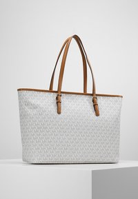 Tasche aus hellgrauem Stoff mit einem ganzflächigen Logo-Muster, versehen mit sandfarbenen Lederakzenten und doppelten Griffen. Strukturierte rechteckige Form.