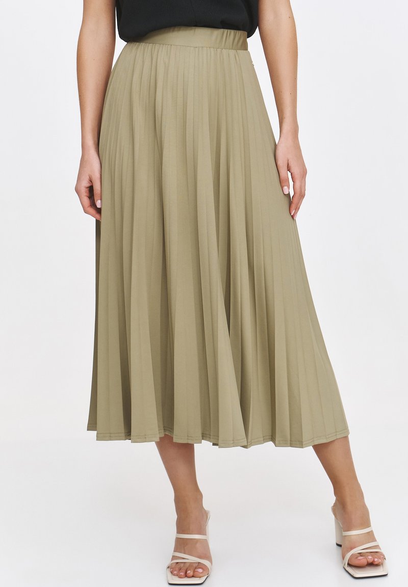 Plisowana spódnica midi w oliwkowym kolorze, charakteryzująca się wysokim stanem i zwiewną teksturą. Połączona z jasnymi, paseczkowymi obcasami w bloku.