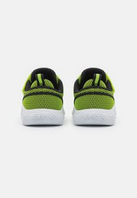 Zapatillas de malla verdes y negras con una suela blanca, que cuentan con un collarín acolchado y una pestaña en el talón para una fácil colocación. En conjunto, son livianas y transpirables.