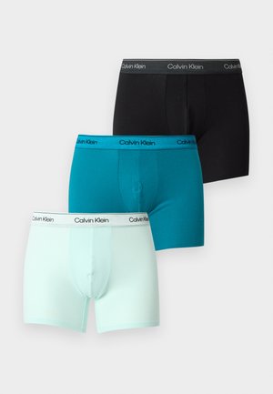Tre Calvin Klein herre boxer briefs i sort, teal og lyseblå, hver med logo-mærkede linninger, vist på en ensfarvet baggrund.