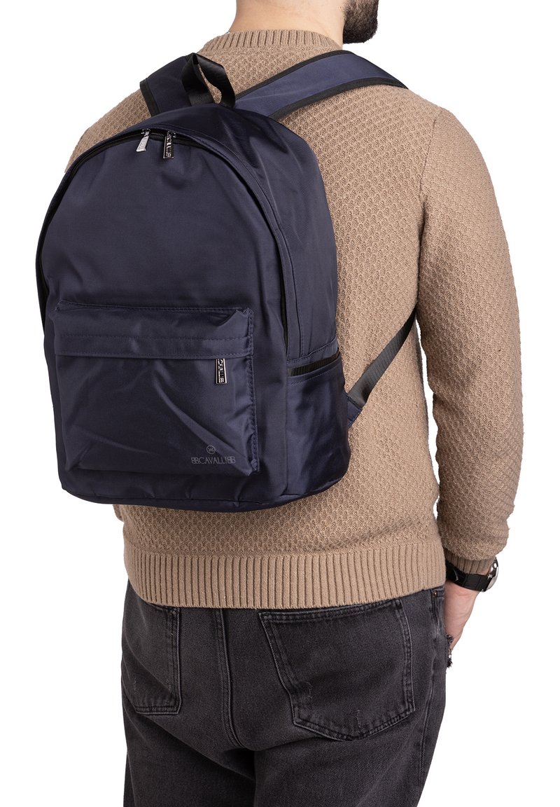 Zaino in tessuto blu navy con una tasca frontale con zip, spallacci regolabili e manico superiore. Texture liscia, design semplice e senza loghi visibili.