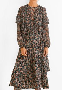 Robe fleurie avec des volants superposés, fond noir, petites fleurs multicolores, manches longues et coupe fluide. Tissu texturé.