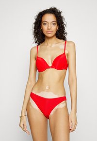 Conjunto de bikini vermelho com um design texturizado em nervuras. O top possui alças finas e um formato triangular, enquanto a parte de baixo tem um corte clássico.