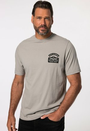 Szary bawełnowy T-shirt z krótkim rękawem, z czarną haftowaną naszywką na lewym klatce piersiowej z napisem „Moto Madness” oraz dodatkowymi tekstami.