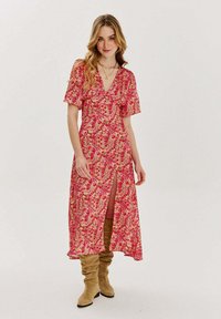 Květinové šaty s krátkými volánovými rukávy; růžový základ s barevným květinovým potiskem; mají hluboký výstřih do V a vysoký rozparek až ke stehnům.