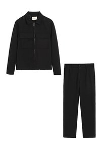 Veste noire avec fermeture éclair et deux poches poitrine ; pantalon noir assorti avec jambe droite et fermeture à bouton à l'avant. Tissu texturé.
