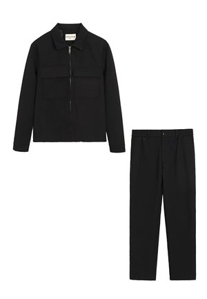 Veste noire avec fermeture éclair et deux poches poitrine ; pantalon noir assorti avec jambe droite et fermeture à bouton à l'avant. Tissu texturé.