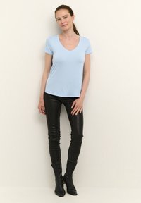 Jasnoniebieska koszulka typu v-neck, krótki rękaw, miękki materiał. Połączona z czarnymi, slim-fit skórzanymi spodniami i botkami sięgającymi kostki z ostrym noskiem.