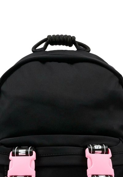 Zaino nero con forma arrotondata, tessuto texturizzato e maniglia superiore avvolta in corda. Include fibbie in plastica rosa con cinghie nere.