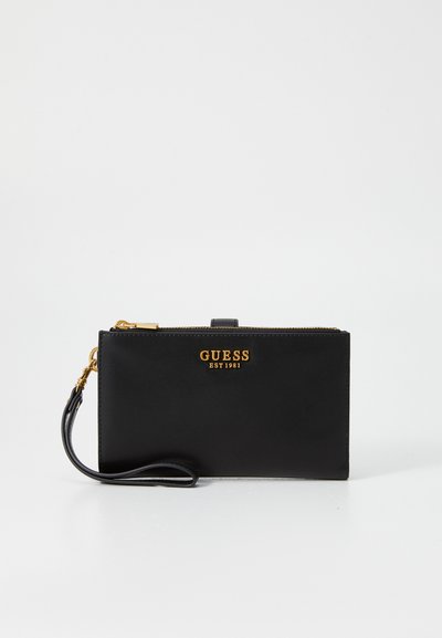 Svart konstläderplånbok med guldlogo, dragkedjestängning och handledsrem. Har en minimalistisk design och slät yta.